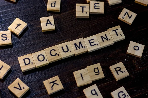 Belgeyi word ile yapılan scrabble harf üzerinde siyah bir ahşap masa.