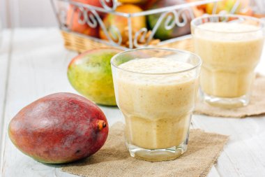 Beyaz masa üzerinde bir bardak taze mango smoothie.
