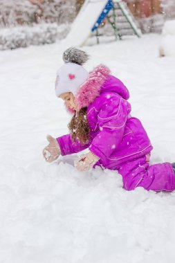 Karlı bir oyun alanında kış üzerinde oynarken küçük çocuk kız.