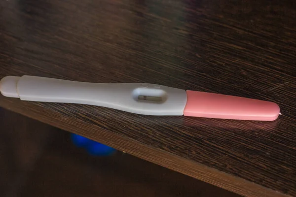 Negative pregnancy test over the brown wooden surface. — Stock Photo, Image