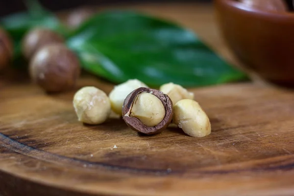 Macadamia καρύδια σε ένα ταμπλό με ξύλινη κουζίνα. — Φωτογραφία Αρχείου
