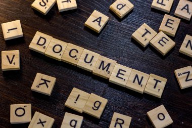 Belgeyi word ile yapılan scrabble harf üzerinde siyah bir ahşap masa.