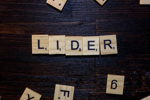 Lider word made with scrabble letters on a black wooden table.