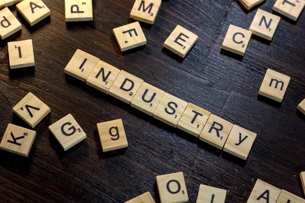 Industry word made with scrabble letters on a black wooden table.