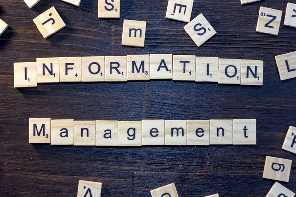 information management word made with scrabble letters on a black wooden table.