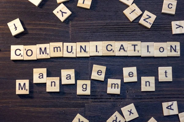 communication management word made with scrabble letters on a black wooden table.