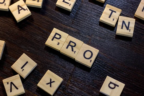 Pro word made with scrabble letters on a black wooden table.