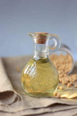 Etrafında soya fasulyesi olan cam şişedeki soya fasulyesi yağı.