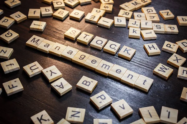 Word or phrase Stock Management made with scrabble letters on black table.
