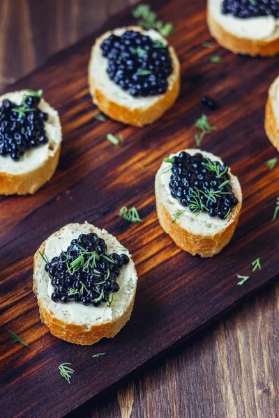 Aperitivo para mesa de Natal - caviar preto nos pedaços de pão . — Fotografia de Stock