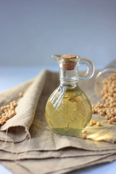 Natural soybean oil in glass bottle with soy beans near it.