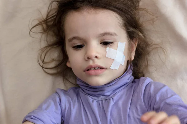 事故後の小さな女の子は、顔に接着剤の小僧で横たわって. — ストック写真