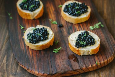 Ahşap mutfak kartı ekmek parçaları üzerinde siyah havyar.