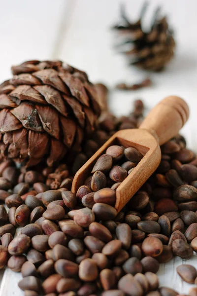 Pine nuts in wooden spoon on a heap of pine nuts.