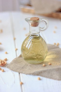 Etrafında soya fasulyesi olan cam şişedeki soya fasulyesi yağı..