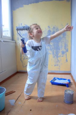 Küçük çocuk kız boya rulo ve ağlama ile duvar boyalar