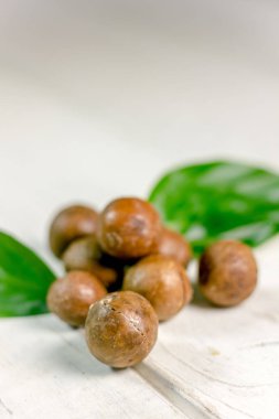 Ahşap masa üzerinde taze ve olgun macadamia fındık.