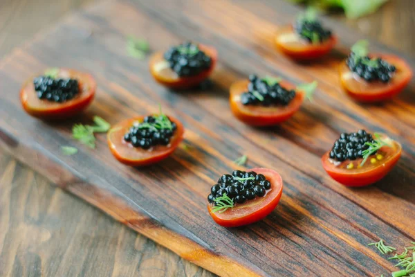 Placa de madeira com os aperitivos de caviar preto — Fotografia de Stock