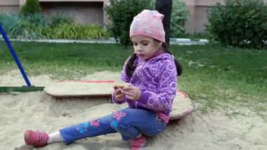 Dışarıda kumlarda oynayan sevimli küçük bir kızın görüntüleri.