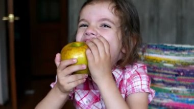 Evde elma yiyen sevimli küçük bir kızın görüntüleri.