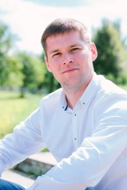 Harika gülümseyen adam parkta oturuyor.