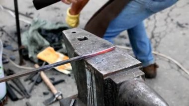 Demirci örste metalle çalışıyor.