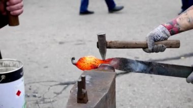İki demirci örs üzerinde metal bir detay dövüyor. 