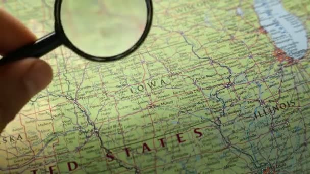 拡大鏡を通して地図上のアメリカ州アイオワ州を見ている人は — ストック動画