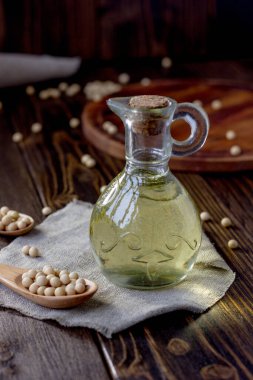 Etrafında soya fasulyesi olan cam şişedeki soya fasulyesi yağı.