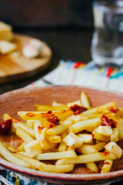 Siyah yüzeyde patates kızartması. Patates, peynir ve soslu Kanada yemeği