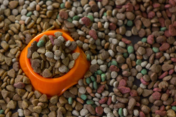 橙色塑料碗 里面塞满了宠物干粮 周围是猫狗用干粮 — 图库照片