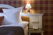 Hotelový pokoj - postel s polštářem a lampami.