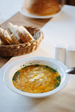 Masadaki beyaz seramik tabakta çorba.