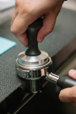 Barista espreso yapmak için metal tutucuda kahve çekiyor.