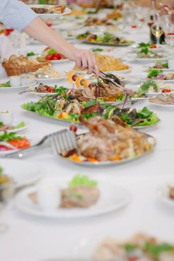 Yemek masası. Elinde maşayla yemek yiyor.