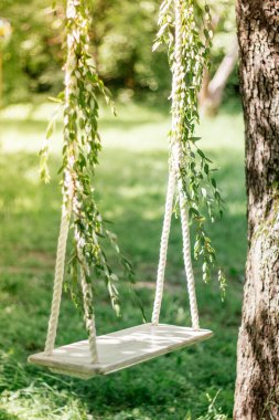 Yeşil ahşap üzerinde düğün fotoğrafı için süslenmiş salıncaklar.