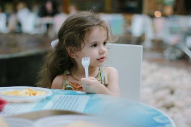 Kafede ya da restoranda elinde plastik çatal olan küçük bir kız..