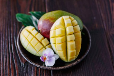 Taze olgun mango yaprakları ve ahşap masanın üzerinde çiçek..