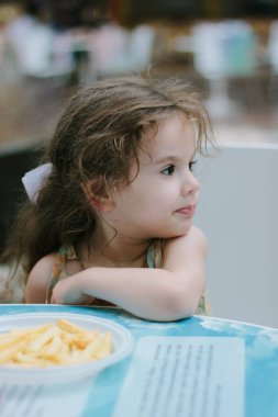 Küçük kız kafede ya da restoranda eğleniyor.