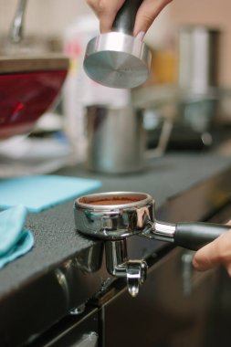 Barista espreso yapmak için metal tutucuda kahve çekiyor.