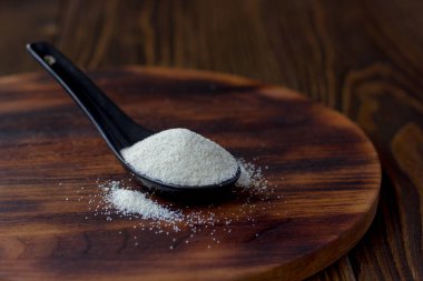 Organik irmik ya da ahşap zemin üzerinde siyah kaşık içinde kuskus buğdayı..