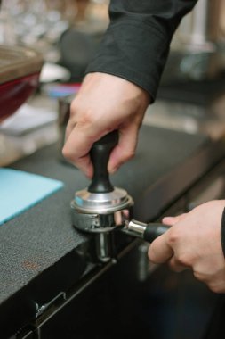 Barista espreso yapmak için metal tutucuda kahve çekiyor.