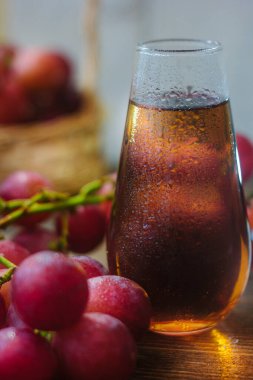 Tahta masanın üzerinde cam içinde üzüm suyu.