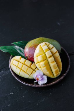 Arkaplanda seramik tabakta mango meyveleri