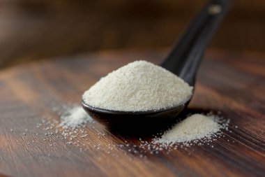 Organik irmik ya da ahşap zemin üzerinde siyah kaşık içinde kuskus buğdayı..