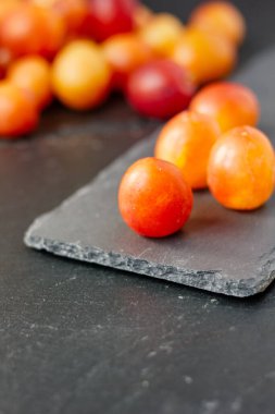 Vahşi erikler siyah taş tahtada meyveler