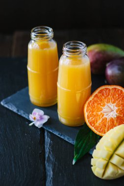 Taze detoks mango ve portakallı smoothie ile dolu cam şişeler..