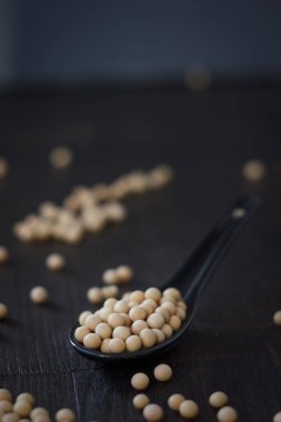Seramik kaşıkta siyah arkaplanda soya fasulyesi