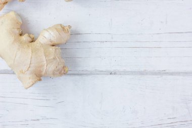 Beyaz ahşap yüzeyde organik zencefil kökü.