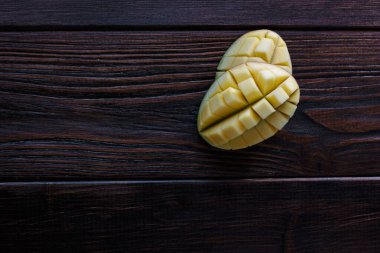 Mango yarıları. Ahşap masanın üzerinde iki parça taze mango meyvesi.